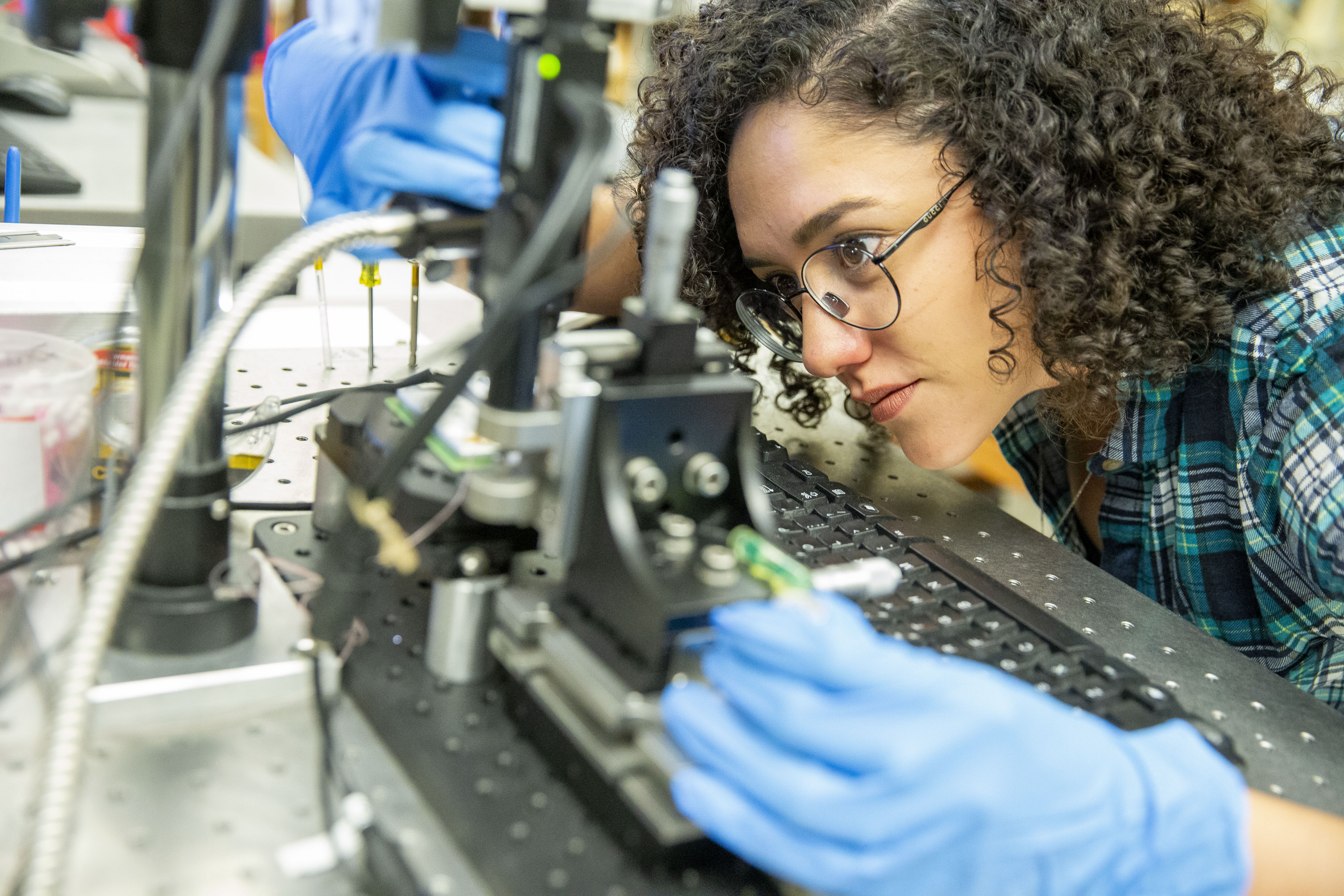 Female student looking intently at mechanical device